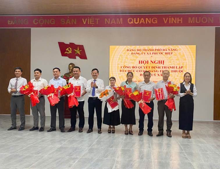 Ảnh: lãnh đạo Đảng ủy trao quyết định và tặng hoa chúc mừng các chi bộ